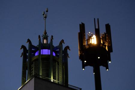 One of the lit flambeau beacons is pictured in front of the bell tower of the Civic Centre. The sky is almost dark.