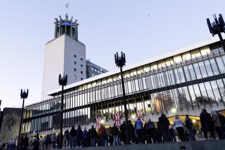 Men, women and children face gather on ceremonial way. They are facing the Civic Centre where the balcony is draped with Union Flags