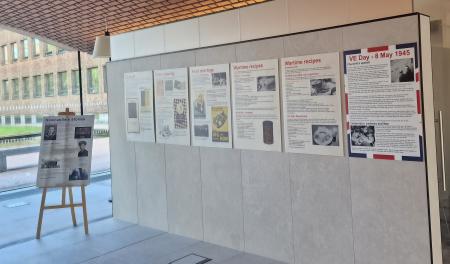 Six display boards on a wall in the Arches at the Civic Centre. Each one focuses on something from World War 2. Another display board is on an easel at the left end of the wall. This board tells the stories of two men who served in the war.