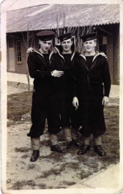 Three men dressed in their navy uniform standing outside a single storey building