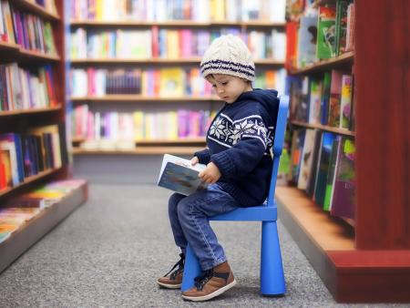 Child reading a book in a library scene