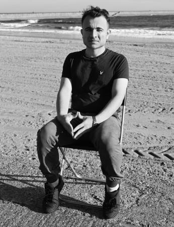 Man sat alone, on a chair, on a beach - part of Where do You Sit exhibition