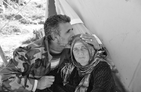 A soldier kisses an older woman on the head sat outside a tent in Iraq