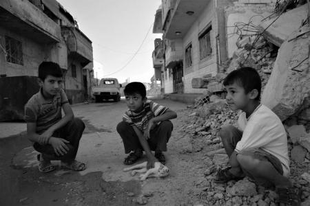 Three young boys play with a kitten in the rubble in Iraqi Kuridstan