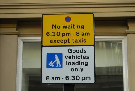 The shared use sign in use for taxis and goods vehicles loading only, the first part of the sign is yellow with a no waiting symbol and states ‘No waiting 6.30pm – 8am except taxis’. Underneath is the standard goods vehicle loading sign which has a picture of loading/unloading symbol and states ‘Goods vehicle loading only 8am – 6.30pm’