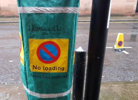 Ticket machine covered with green hood, the hood has the no waiting symbol and states ‘no loading Parking place suspended’