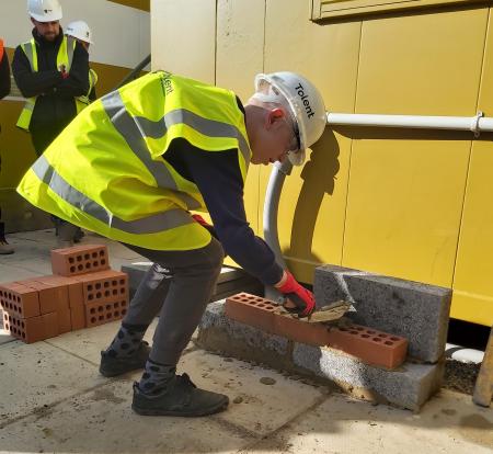 Local school pupil has a go at laying bricks