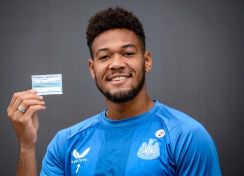 Newcastle United star Joelinton holding his vaccine card 