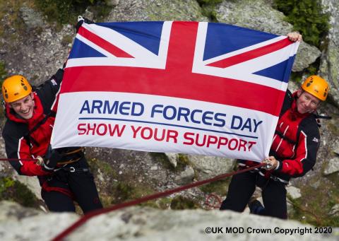 Soldiers holding an Armed Forces Day flag on a mountain