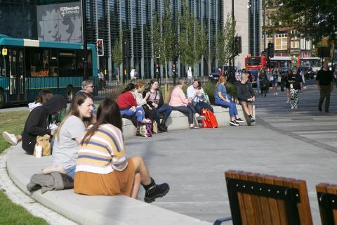 Photos shows people sitting and socialising in a new public space that was once dominated by traffic.