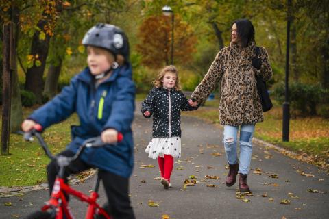 image of child cycling with mother and sister in the background