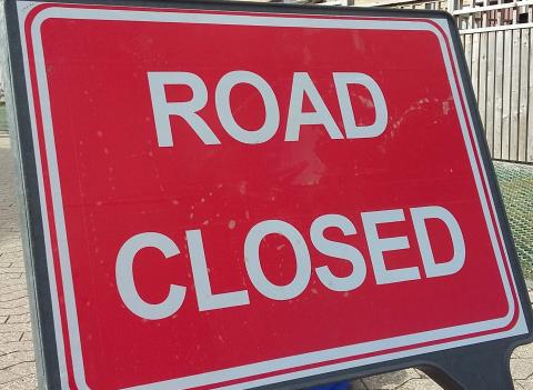 A red road sign with the words Road Closed on it.