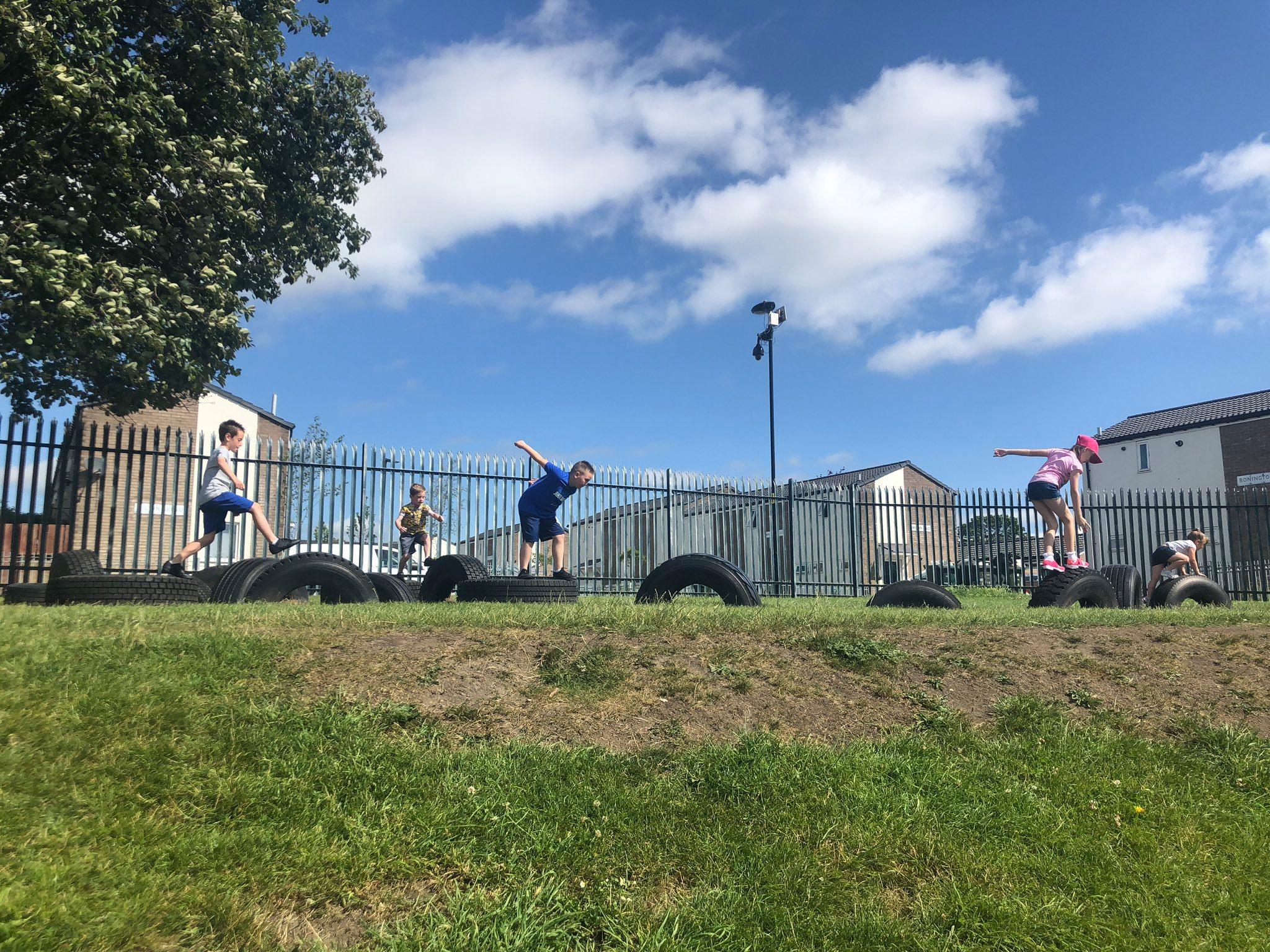 children jumping over tyres 