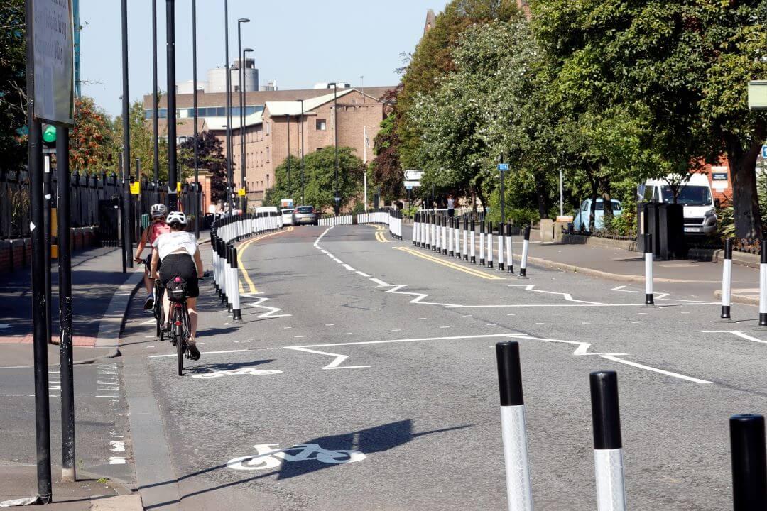 Photo shows temporary cycle lanes marked out using black and white traffic cones along the side of Queen Victoria Road in Newcastle.