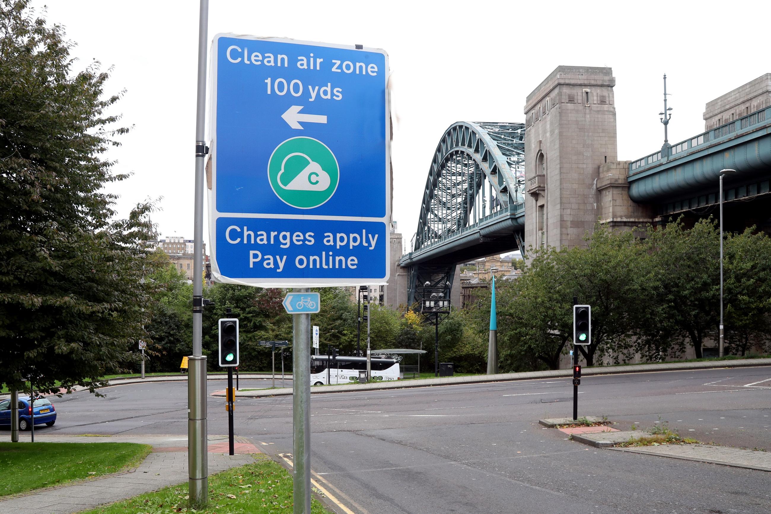 Photo shows a blue road sign with information about the Newcastle and Gateshead Clean Air Zone on it and the Tyne Bridge in the background.