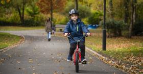 A child riding a red bicycle in a park