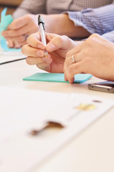 Two people writing on post-it notes