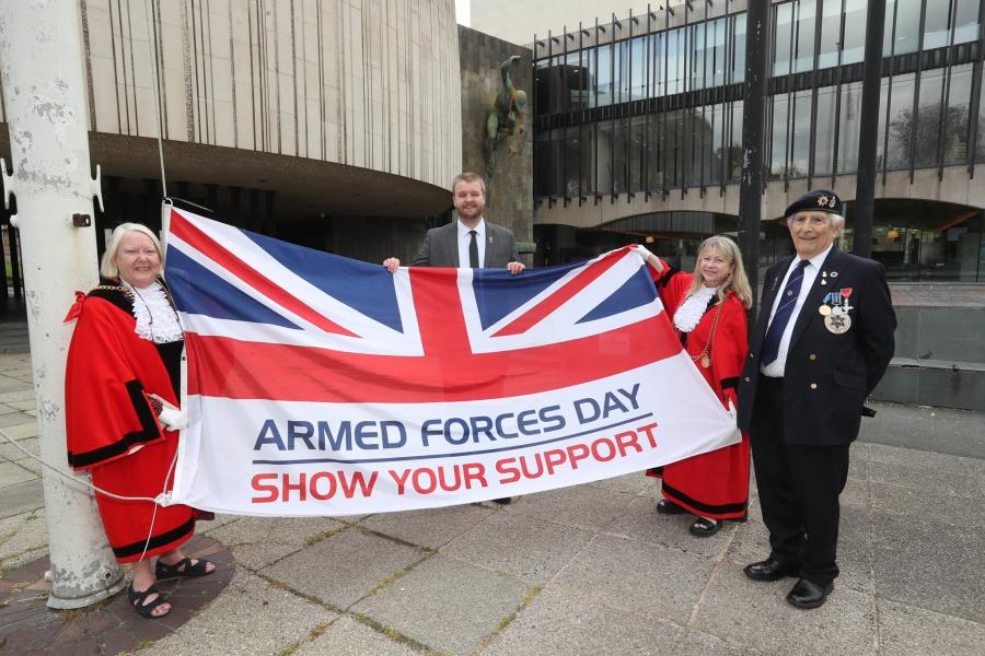 The Lord Mayor and Sheriff of Newcastle and the Armed Forces Champion hold the Armed Forces Day flag before it is raised at the Civic Centre as a veteran watches 
